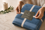 Willow & Fern Luxury Bath 700 GSM towel set in blue being tied with ribbon
